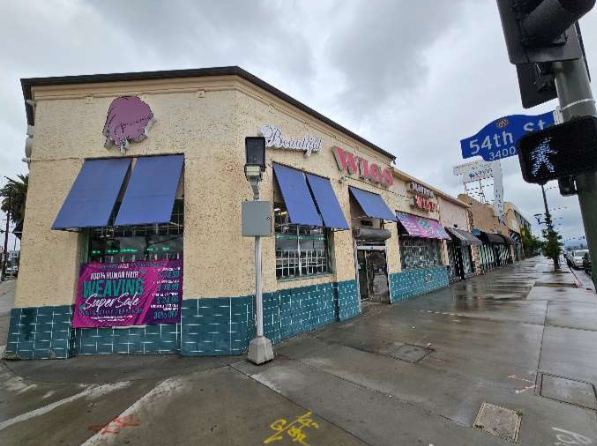 The corner wig shop at 54th Street with blue awnings on a rainy day.