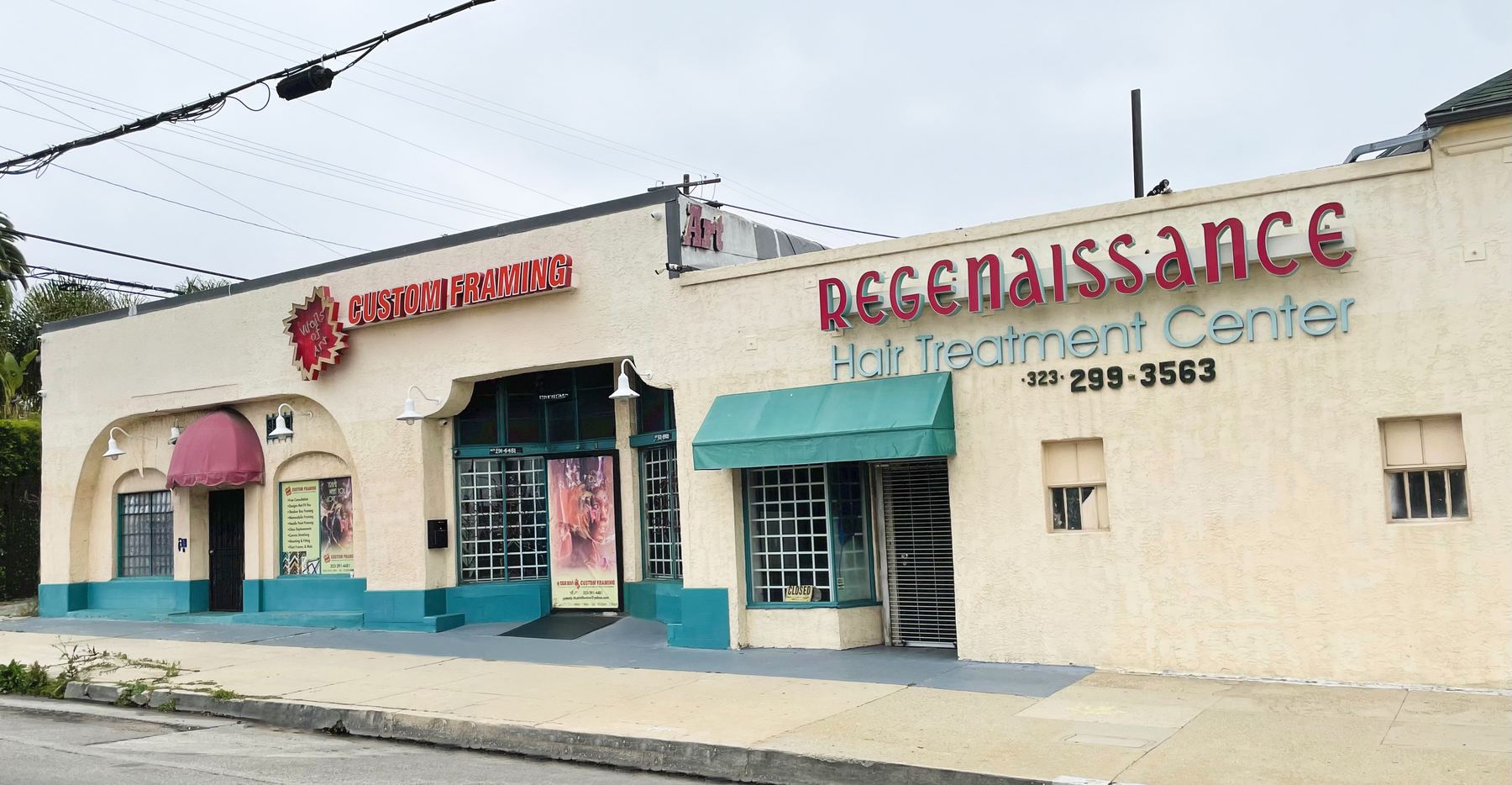The building in its final years: Regenaissance Hair Treatment Center sign in red script beside a custom framing shop, teal trim, overcast sky.